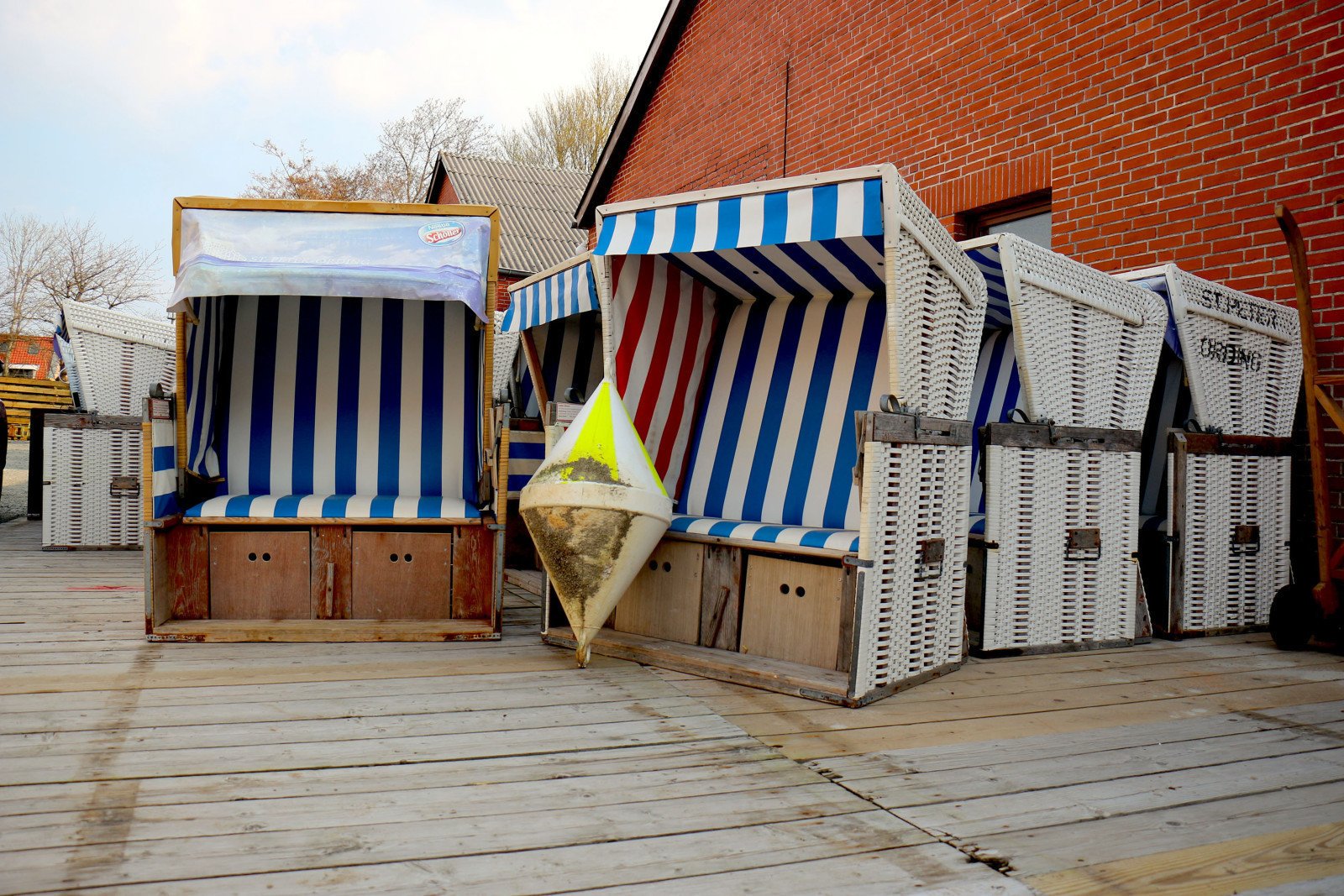 Strandk&ouml;rbe stehen gesammelt vor einem roten Backsteingeb&auml;ude.