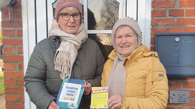 Zwei Personen in Winterjacken und Mützen vor einer Haustür mit Briefkasten