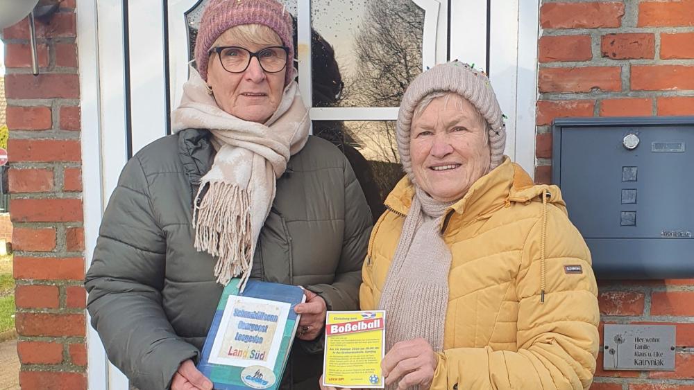 Zwei Personen in Winterjacken und Mützen vor einer Haustür mit Briefkasten