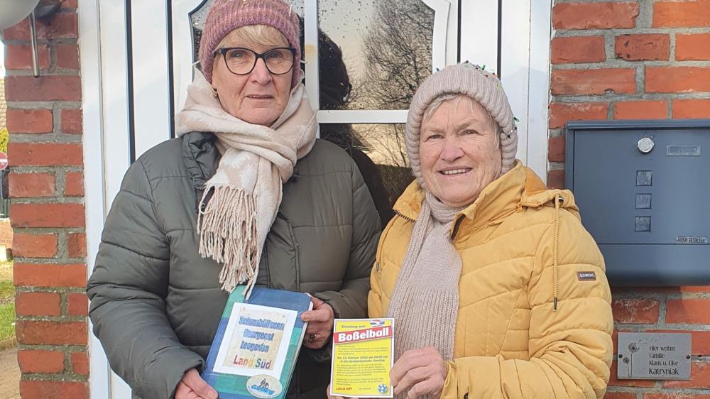 Zwei Personen in Winterjacken und Mützen vor einer Haustür mit Briefkasten