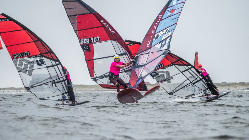 Winsurfer vor St. Peter-Ording. Im Hintergrund ein Pfahlbau.