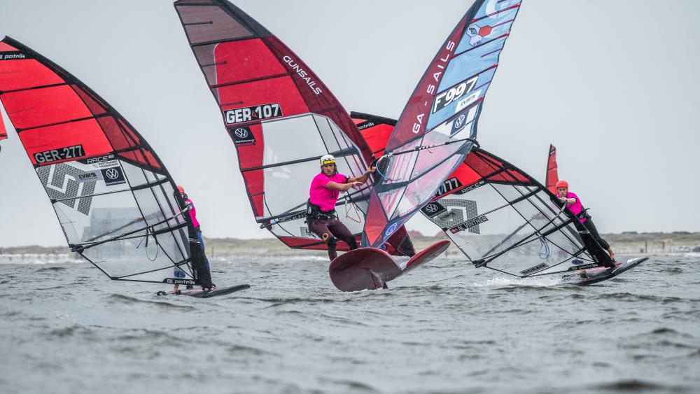 Winsurfer vor St. Peter-Ording. Im Hintergrund ein Pfahlbau.