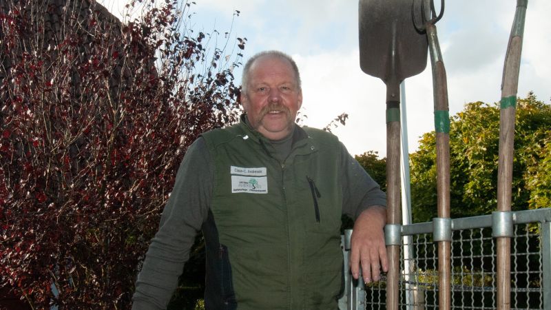 Ein Mann vor einer Hecke.