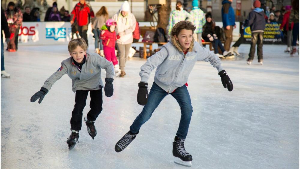 Zwei Kinder auf einer Eisbahn.