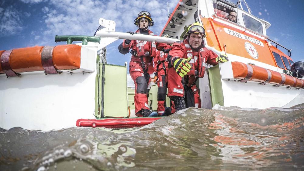Menschen auf dem Senotretter-Boot Paul Neisse. Ein Mann streckt seine Hand aus.