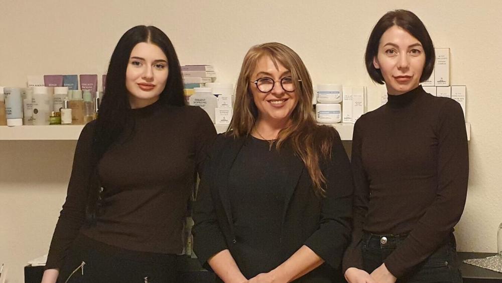Drei Frauen stehen in einem hellen Raum.
