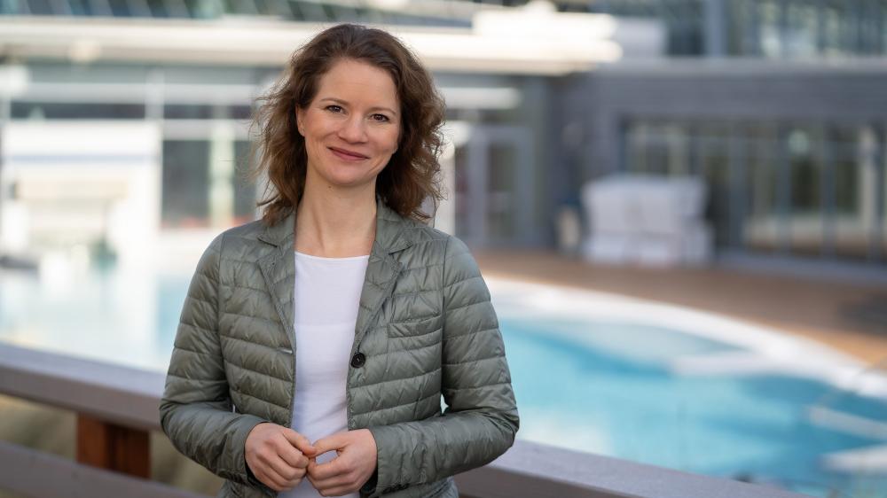 Eine Frau in Softshell-Jacke steht vor einem Außenpool