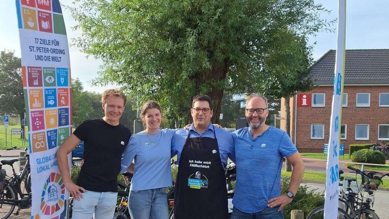 Drei Männer und eine Frau stehen auf dem Marktplatz in St. Peter-Ording.
