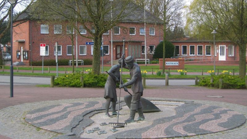 Brunnenplastik „Jan und Gret“ (zum Aufnahmezeitpunkt ohne Wasser) vor dem Rathaus von Sankt Peter-Ording (Dorf) in Schleswig-Holstein, Deutschland.